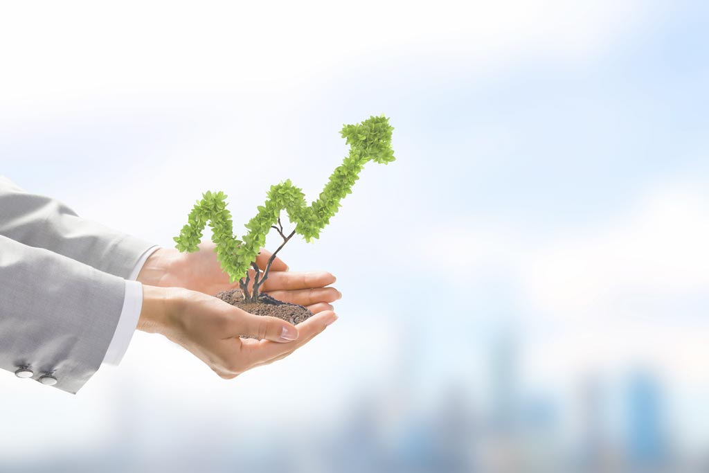 hands of person in suit holding miniature tree in shape of upward trend graph